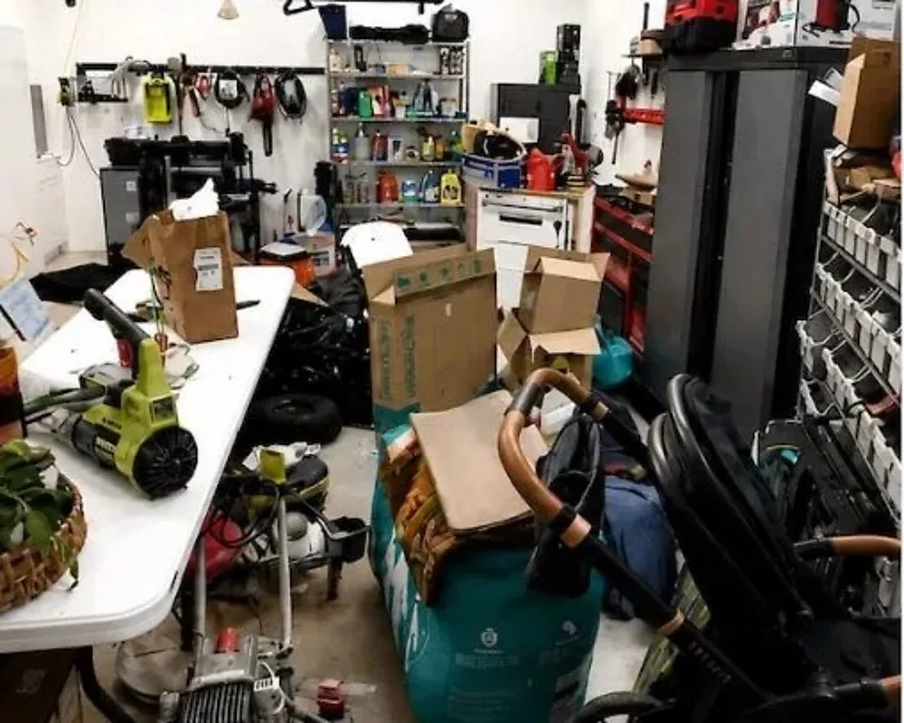 Before: the same garage with boxes, a stroller, and tools covering the floor, its back shelves waiting behind the clutter